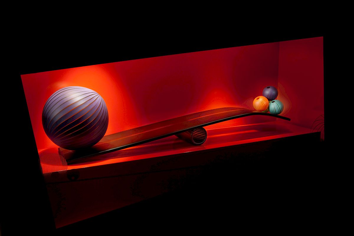 A red-lit display with variously sized, colorful spheres positioned on a curved, wooden-like surface, creating a visually appealing arrangement.