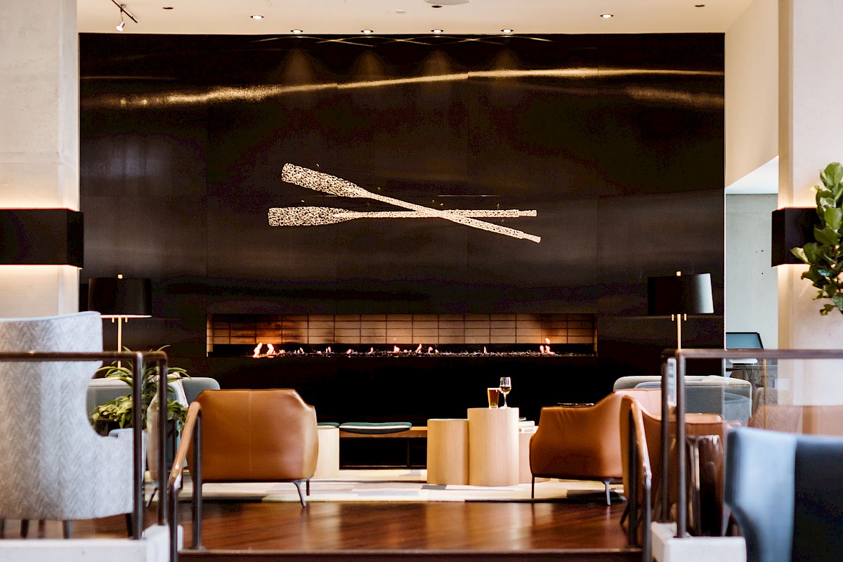 A modern lounge area with contemporary seating, a black wall art piece featuring crossed sticks, and a cozy ambiance.