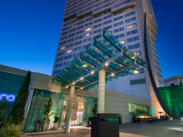 A modern building with glass entrance and architectural features, illuminated at night.