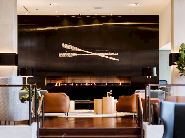 This image shows a modern lounge area with stylish seating, a wall art installation, steps leading to a cozy area, and warm ambient lighting.