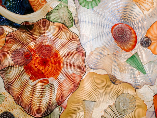 A colorful and detailed display of glass art with various shapes and patterns, featuring intricate swirls and textures in a variety of hues.