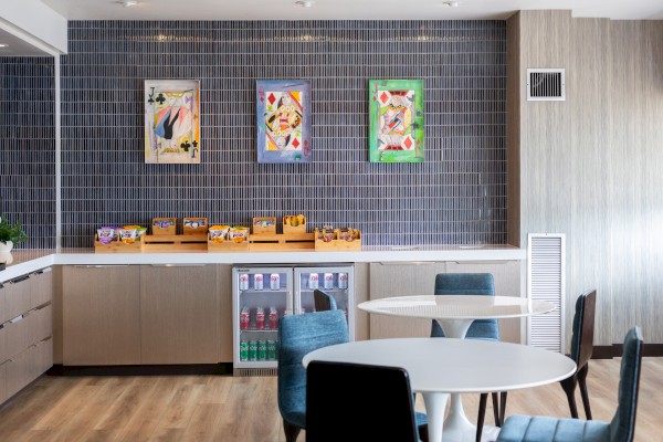 A breakfast area with colorful Playing Card-themed artwork, snacks, and drinks on a counter, surrounded by tables and chairs.