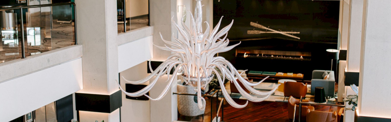 A luxurious hotel lobby features modern furniture, a large chandelier, and a cozy seating area with warm lighting.